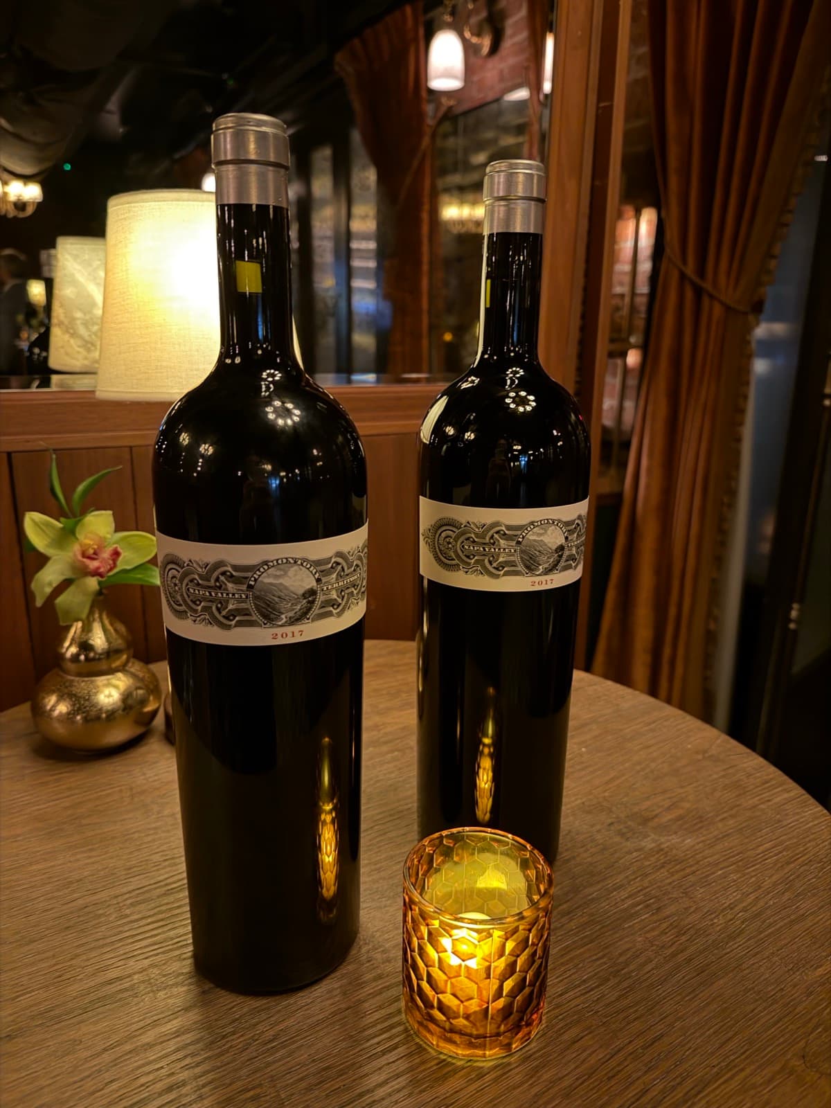 Two dark bottles with ornate calligraphy labels on a restaurant table